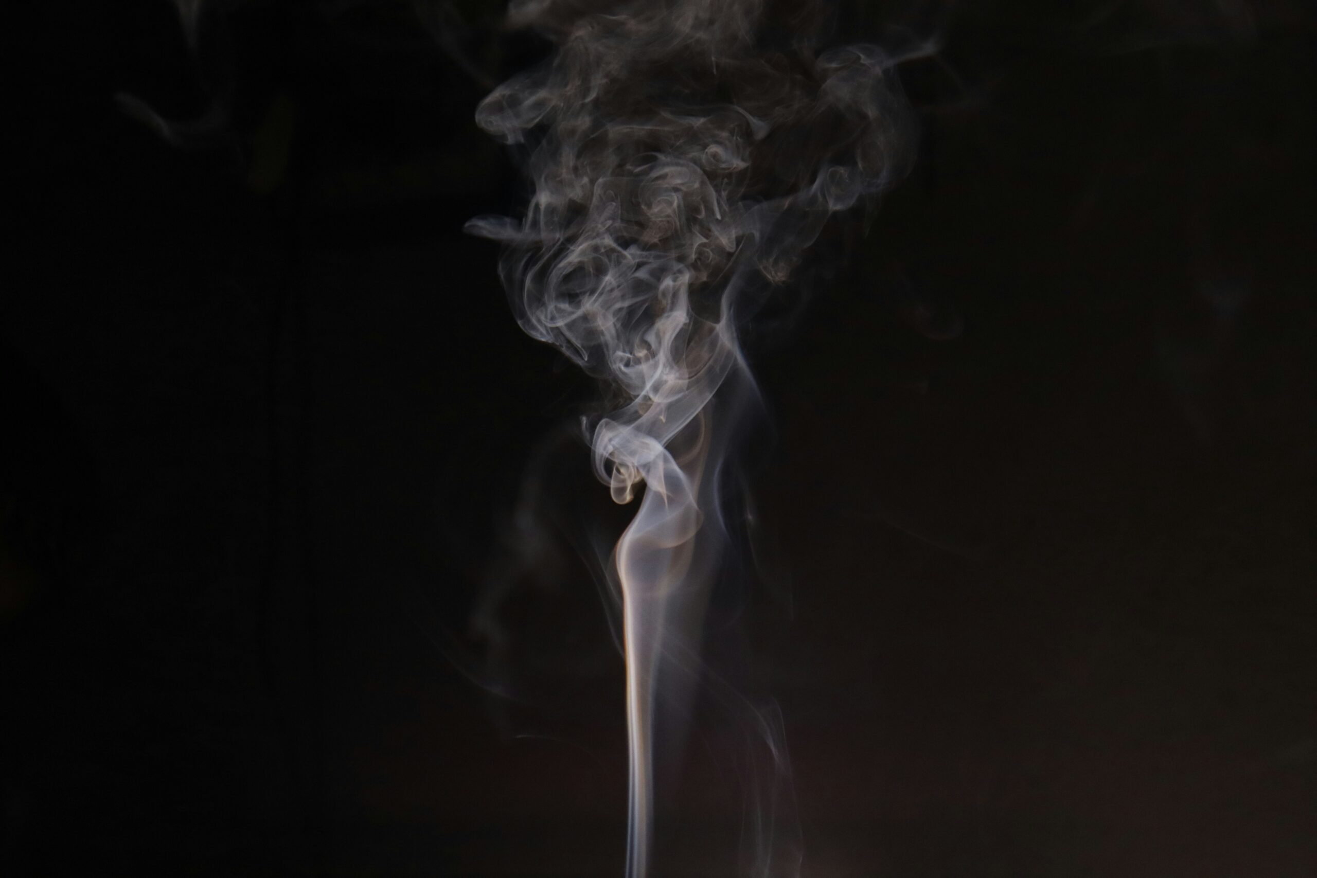Eine gerade, vertikal aufsteigende Rauchsäule vor dunklem Hintergrund als Symbol für energetische Ausrichtung und Fokus.